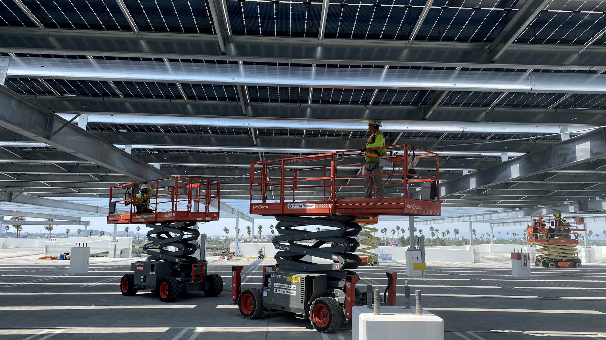 Construction of the garage-top canopy structure at Intuit. Construction workers are on top of machines installing the roof.