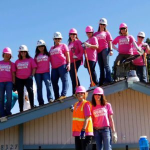 Women Build team standin on roof all wearing pink shirts