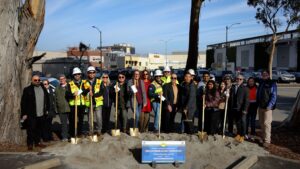 Construction workers and other people posing in front of the Groundbreaking Ceremony plaque for SM-82